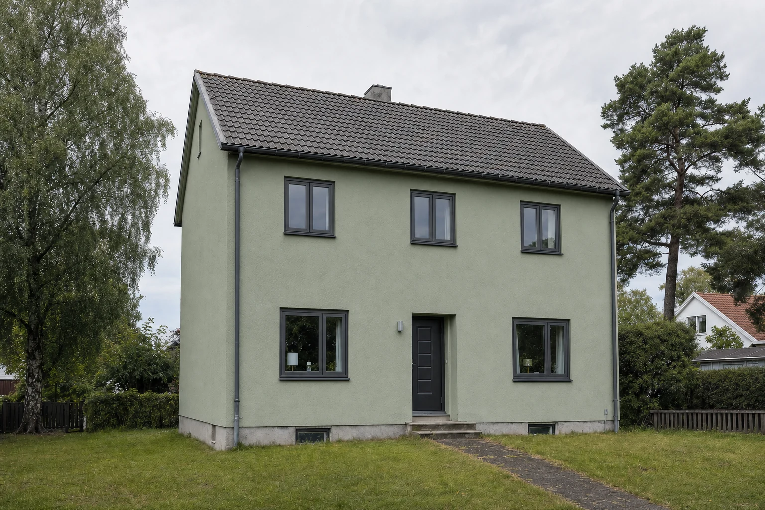 The same house with sage-green render and dark grey window frames